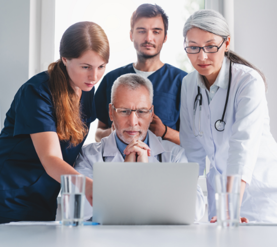 A team of uro-uncologists gathered around a laptop screen, reviewing non-muscle-invasive bladder cancer pathology results  
